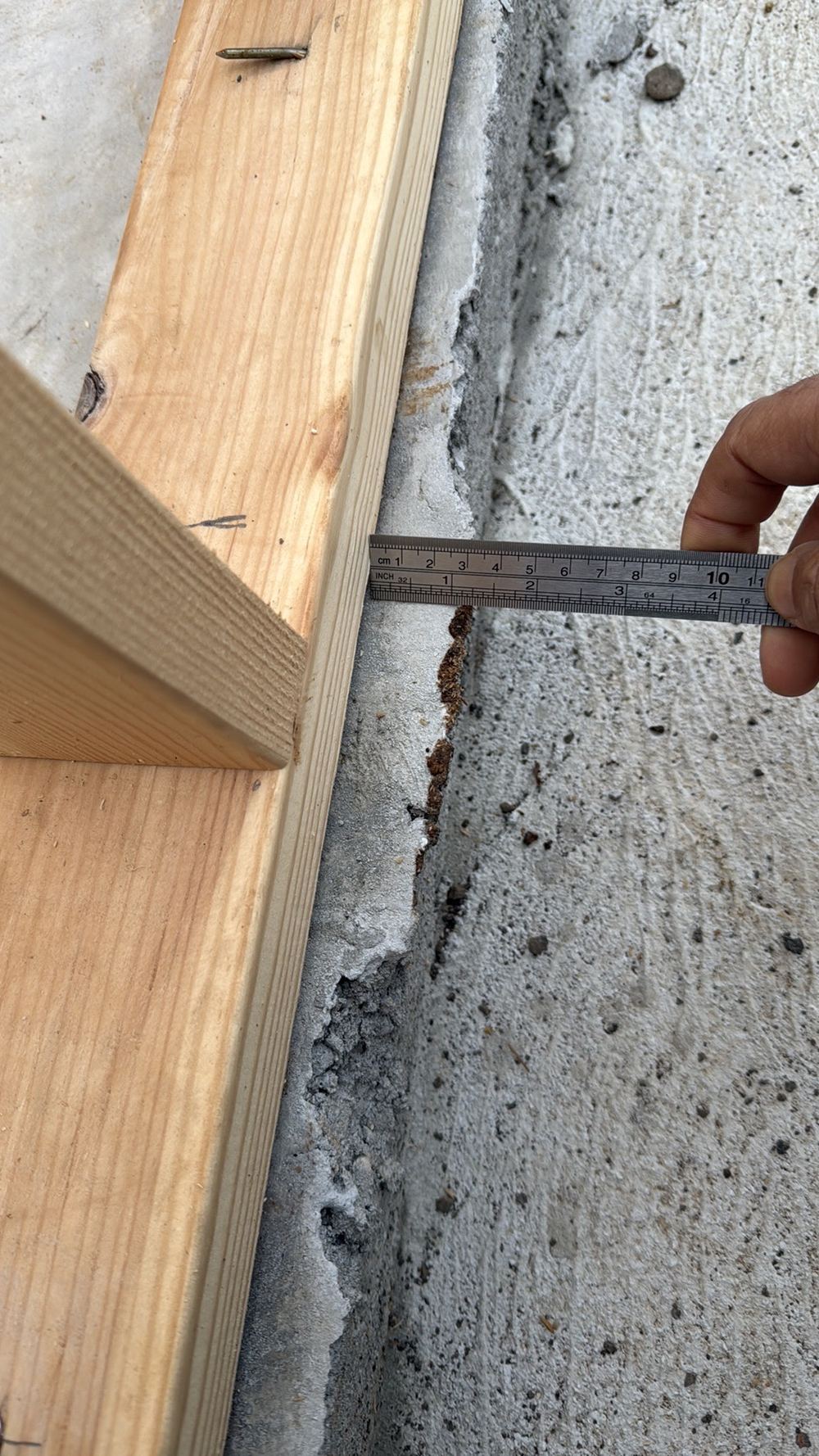 Slab edge standing more than 20mm past the frame, narrowing the brick cavity, found during a frame inspection in Aintree